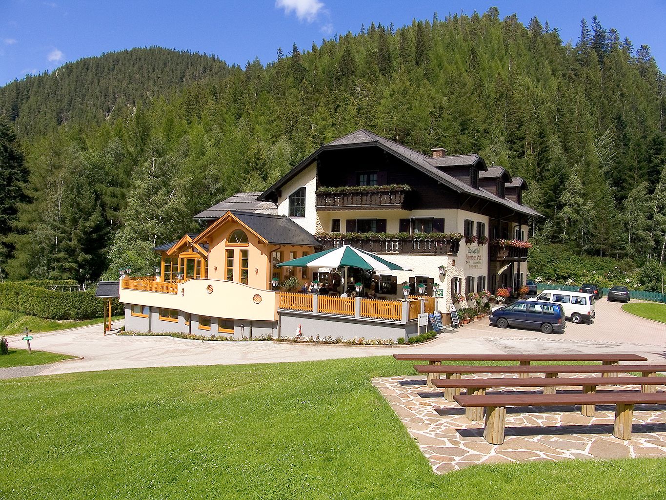 Alpengasthof Kummerbauerstadl v horách s terasou a auty.