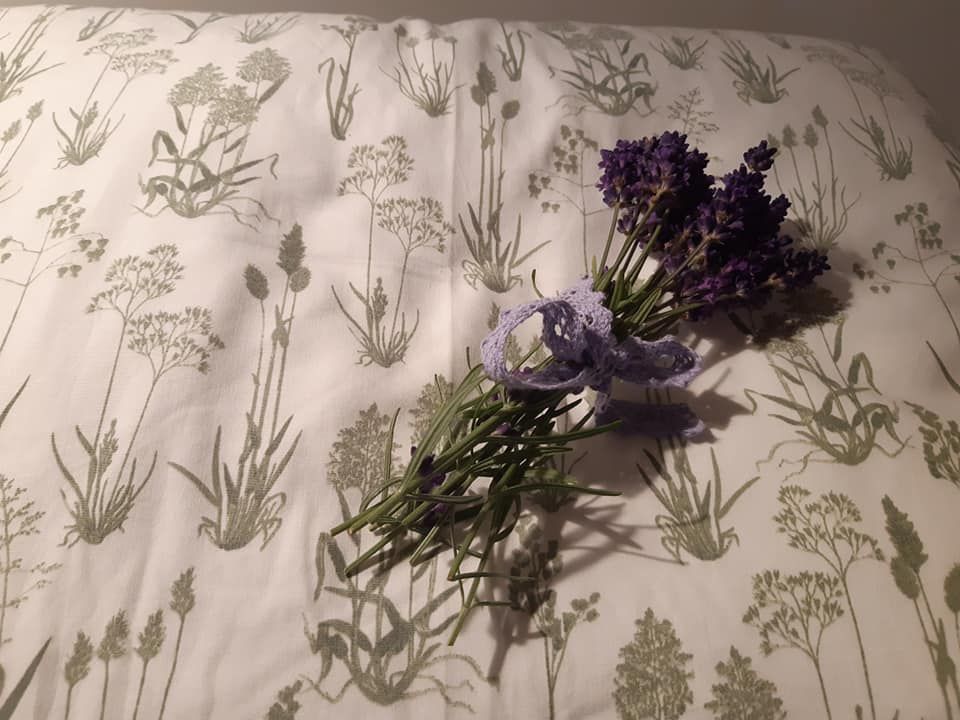 Na polštáři s rostlinným vzorem leží svazek levandule.