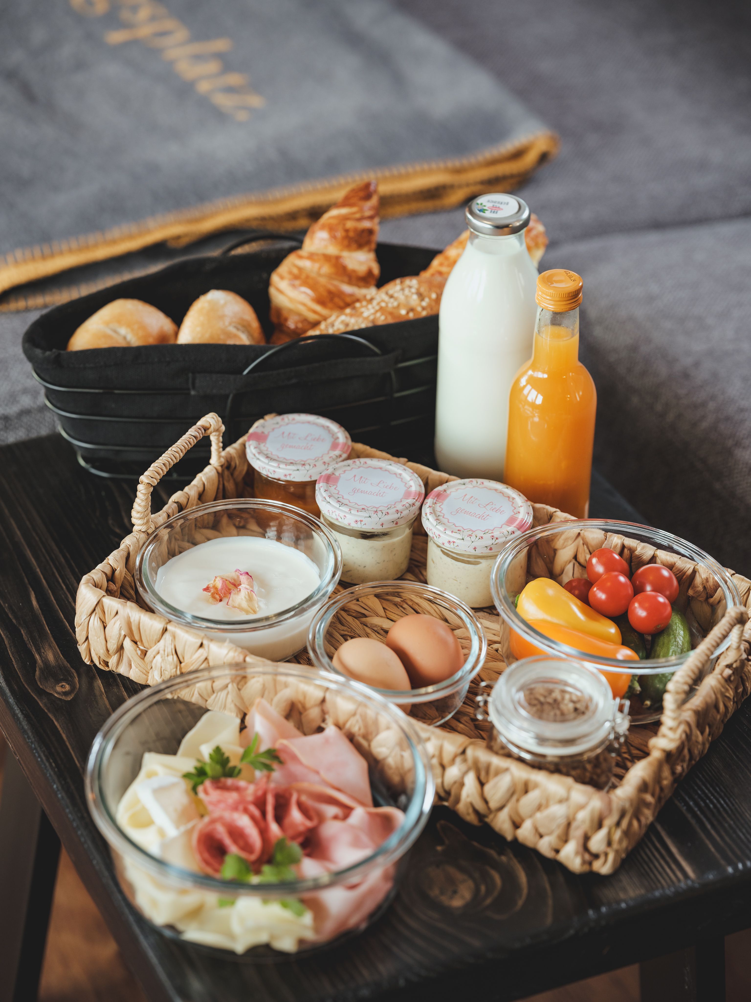 Snídaňový podnos s rohlíky, croissantem, mlékem, džusem, jogurtem, vejci, uzeninami a zeleninou.