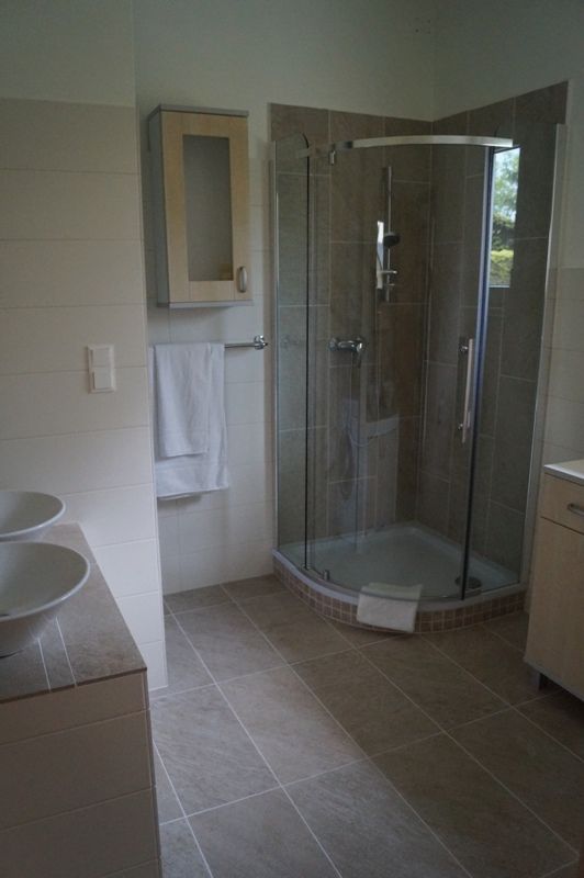 Moderní koupelna se sprchovým koutem, umyvadlem a věšákem na ručníky.