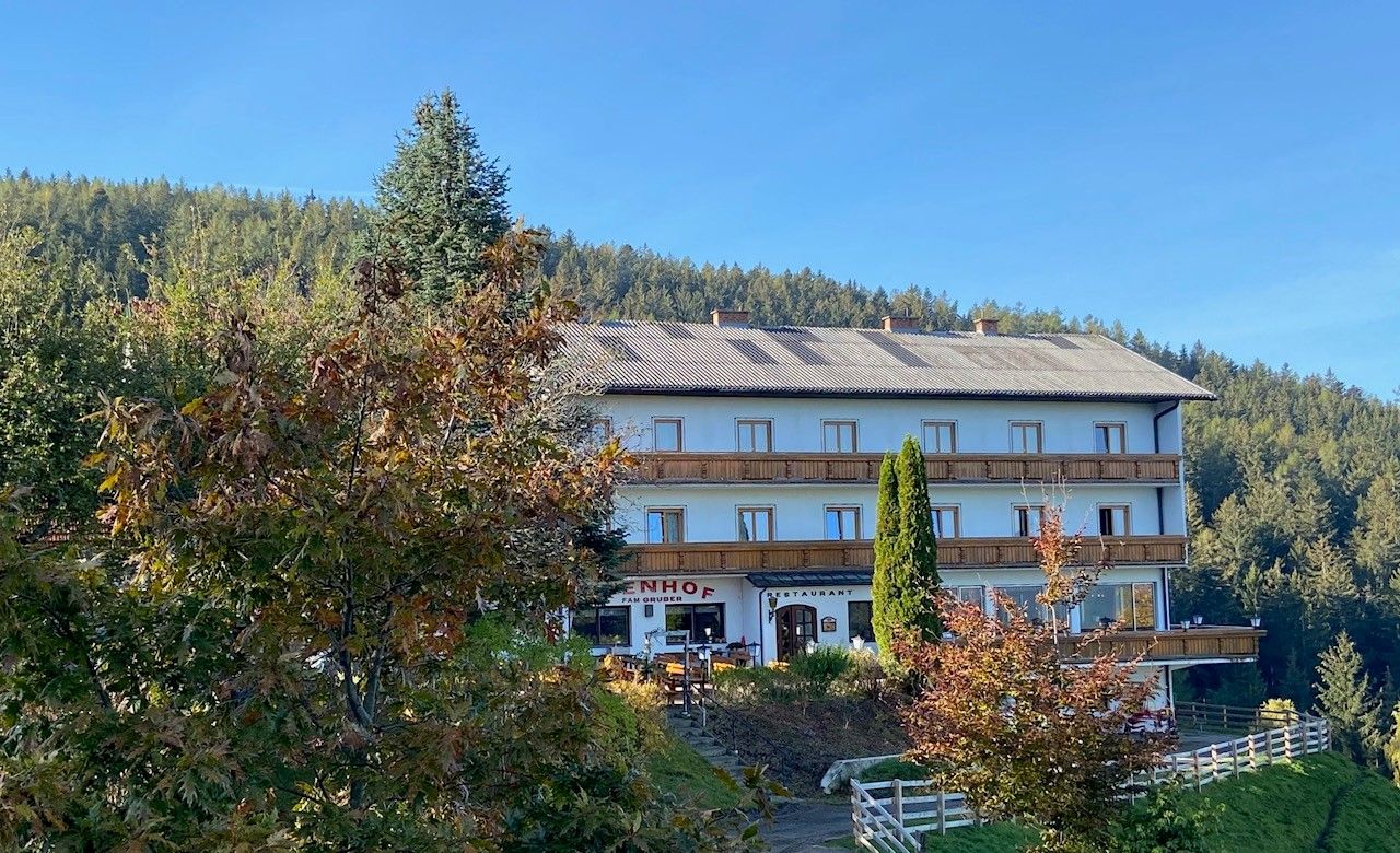 Gasthof-Pension Ödenhof před zalesněným kopcem.