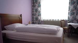 Jednoduše zařízený hotelový pokoj s postelí, stolem a židlí.