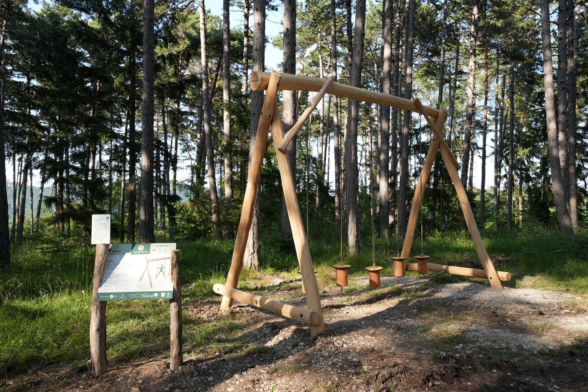 Dřevěné zařízení v lese s informační tabulí v léčivém lese Göttweig.
