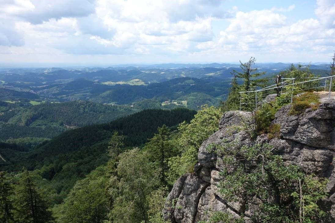 Pohled z kamenné hradní zdi na zalesněné kopce a údolí.