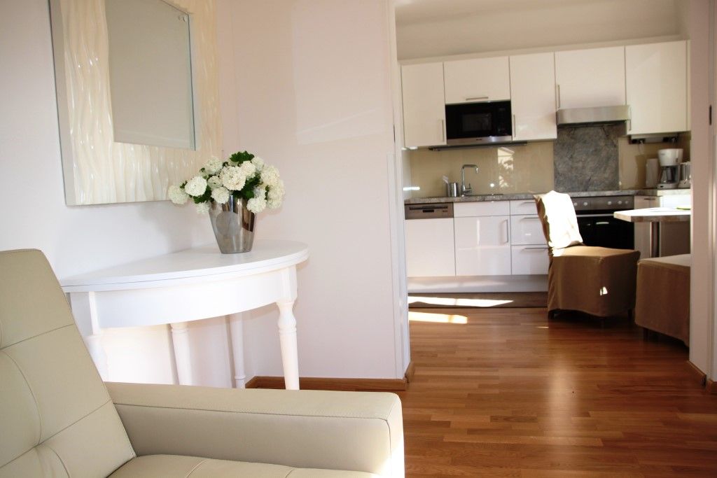 Pohled do interiéru moderního obývacího pokoje s kuchyní a květinami na stole.