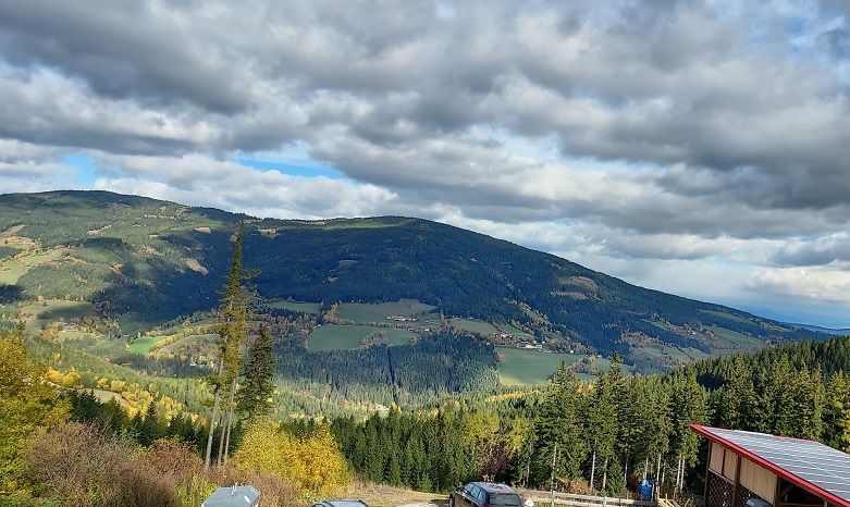 Panoramatický pohled na kopcovitou krajinu s lesy a poli pod zataženou oblohou.