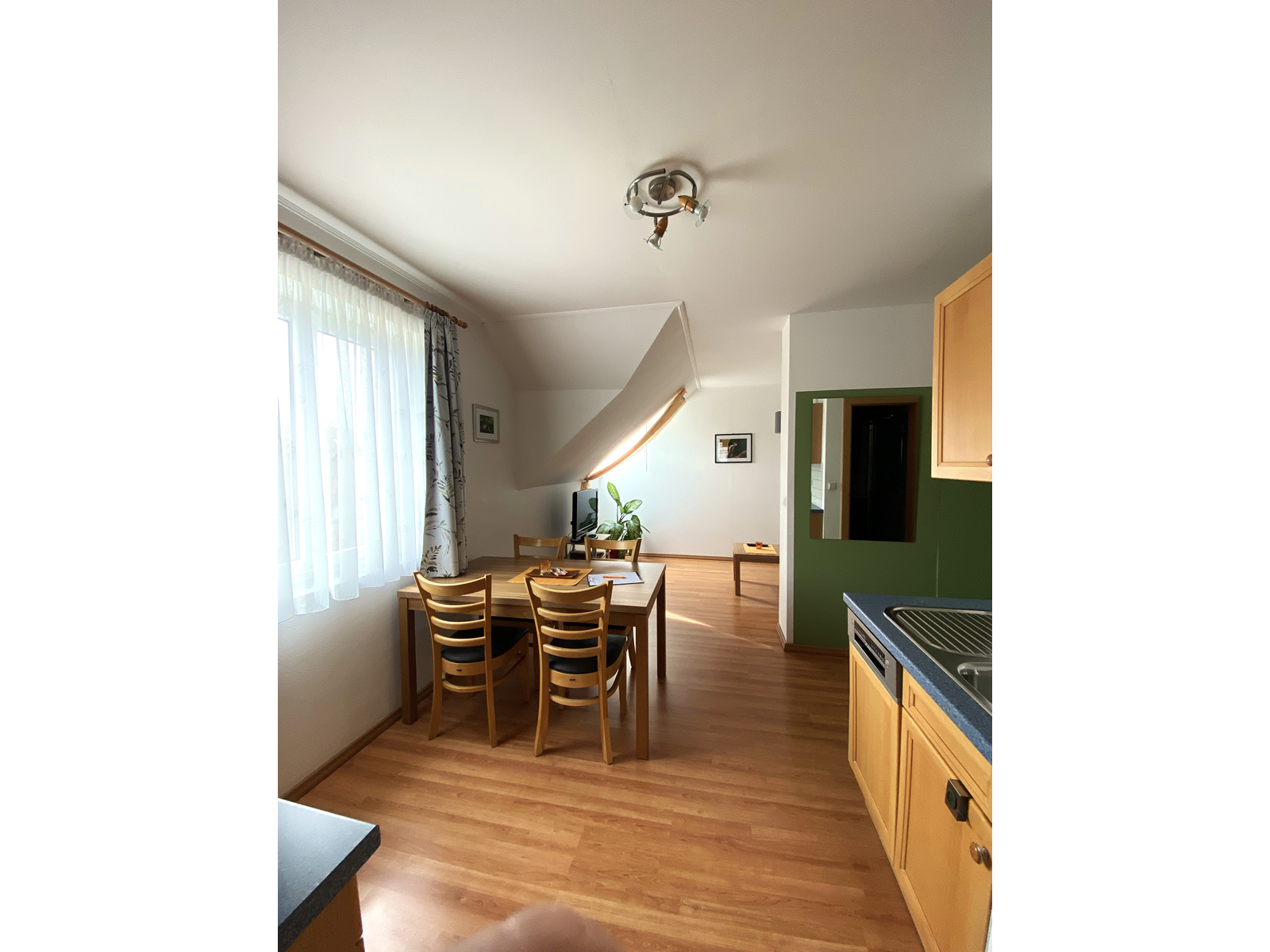 Pohled do interiéru rekreačního bytu s jídelním stolem, židlemi a kuchyňským koutem.