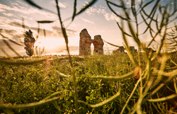 Die sanften Hügel umrahmen die beeindruckenden Ruinen, die im warmen Licht der Abendsonne erstrahlen. Ein Gefühl von Geschichte und Mystik durchdringt die Luft, während die Wiesen mit bunten Wildblumen blühen und die Natur in voller Pracht erblüht.