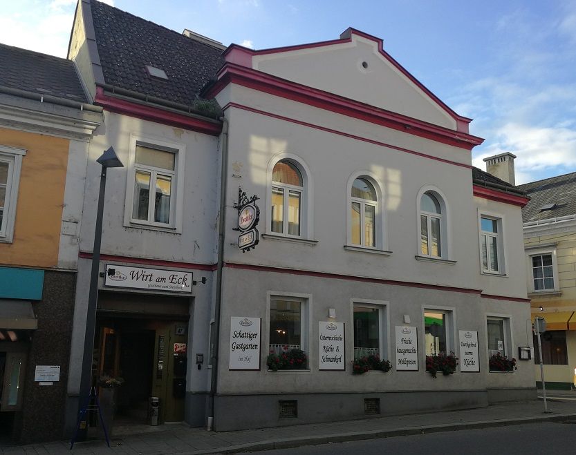 Hostinec s nápisem "Wirt am Eck" na rohu ulice.