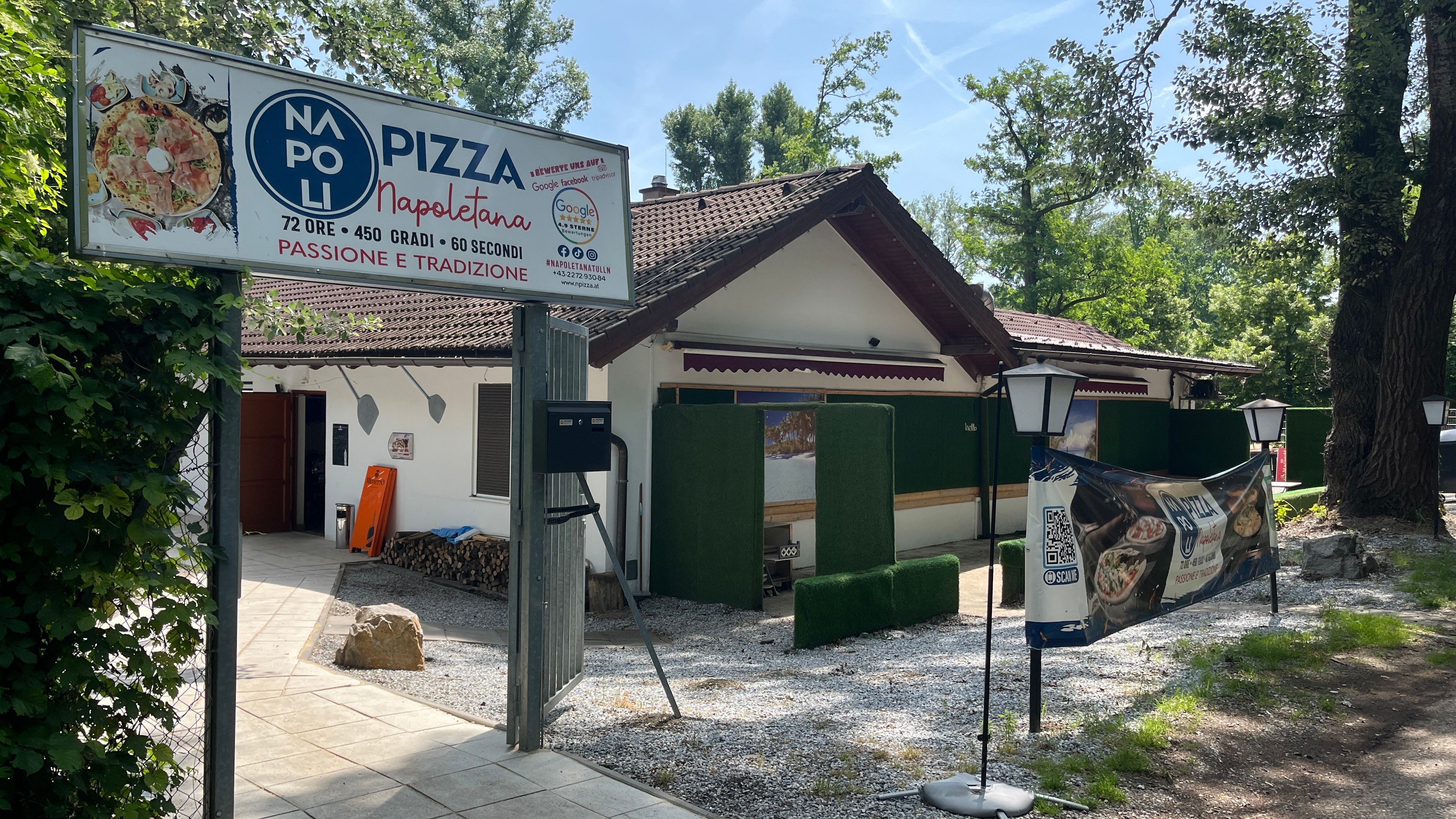 Vstupní prostor při pohledu z parkoviště. Vstupní brána s velkým nápisem pizzerie a lucernami.