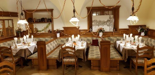 Tradičně zařízená restaurace s dřevěným nábytkem a zdobenými stoly.