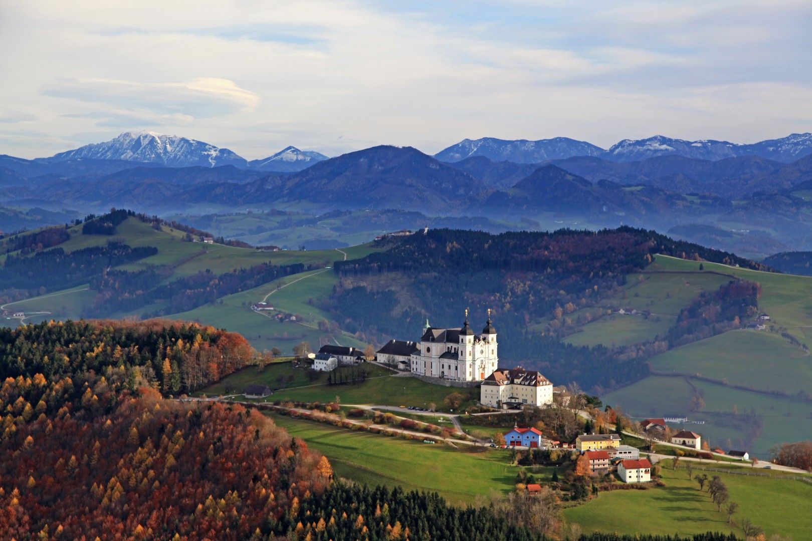 Panoramatický pohled na Mostviertel s bazilikou Sonntagberg v popředí a horami v pozadí.