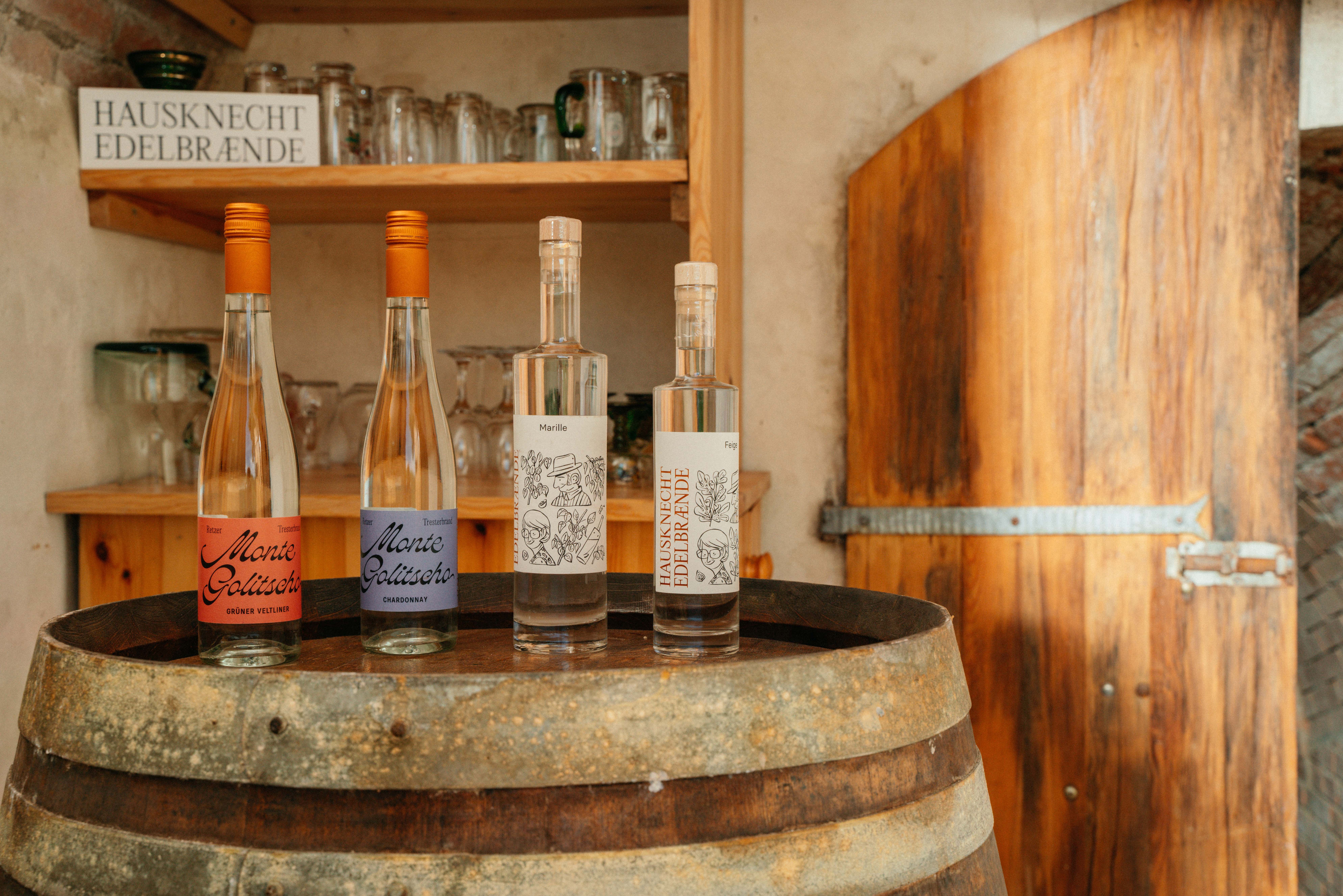 Tři láhve brandy na dřevěném sudu v rustikální místnosti.