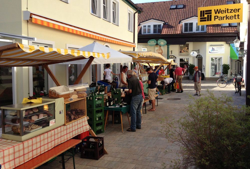 Farmářský trh v pasáži se stánky a návštěvníky.
