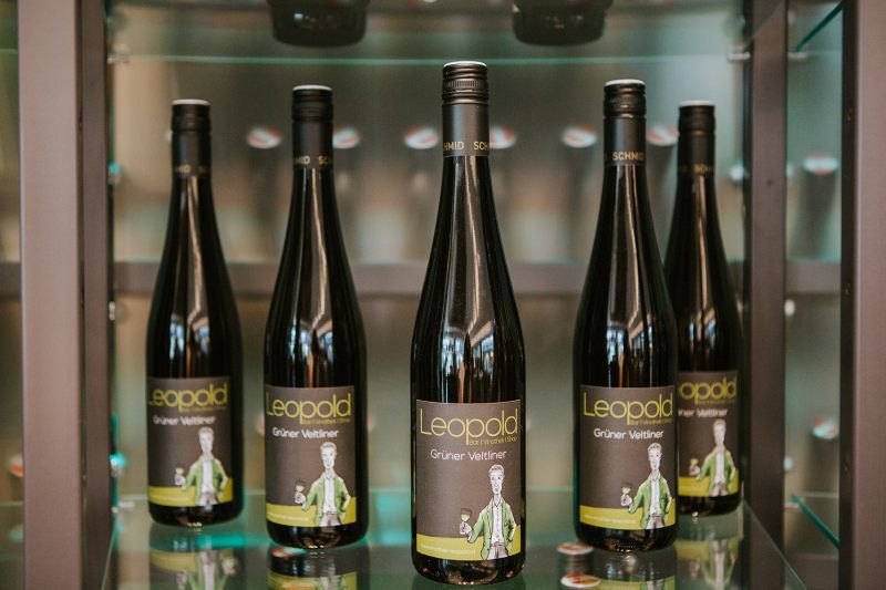 Pět lahví vína veltlínské zelené značky Leopold na polici.