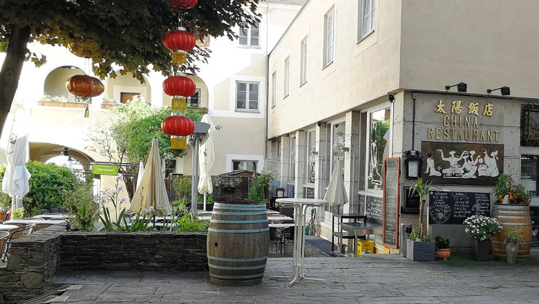 Čínská restaurace s červenými lucernami a venkovním prostorem.