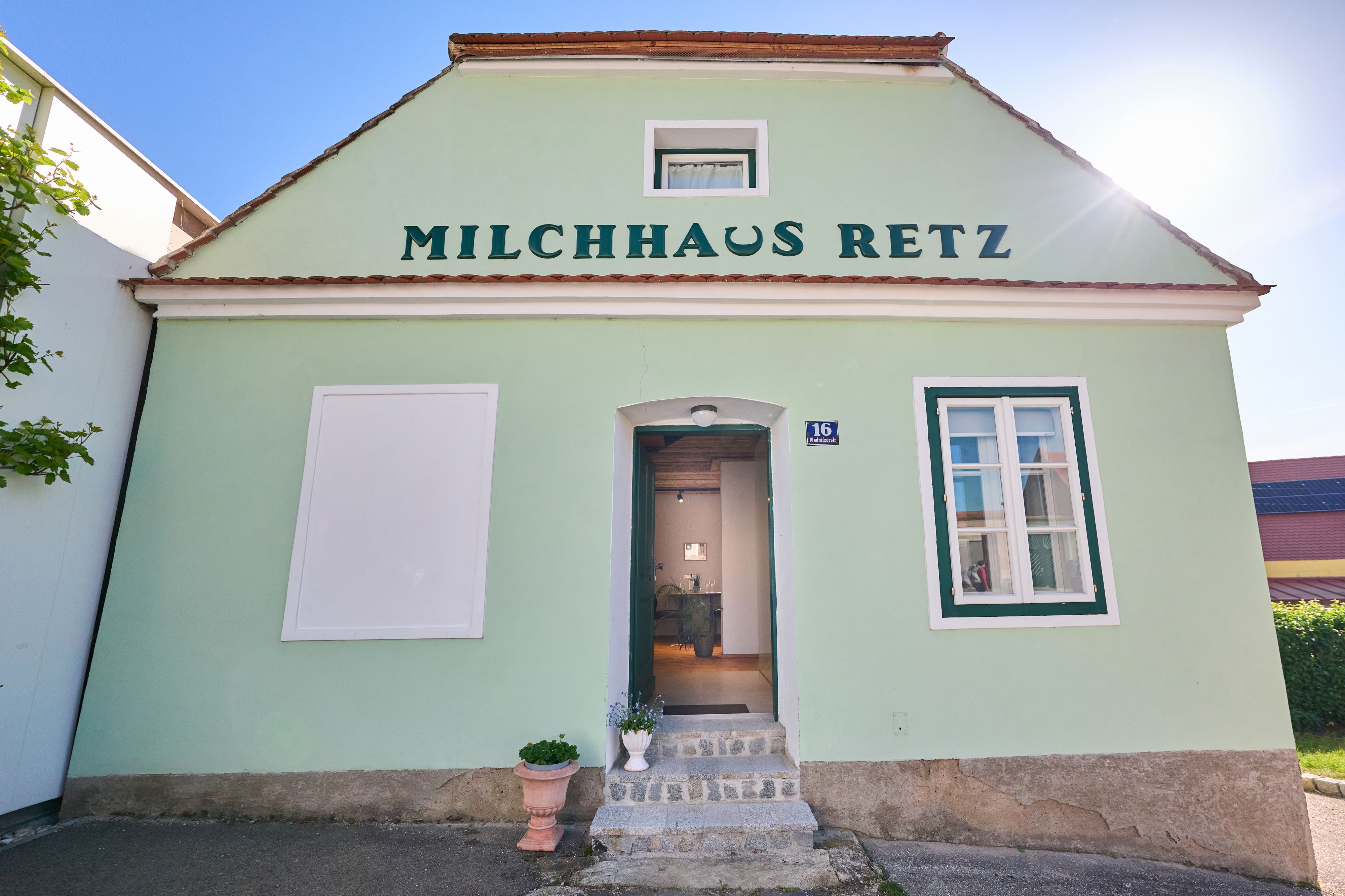 Zelená budova s nápisem "Milchhaus Retz" a otevřenými dveřmi.