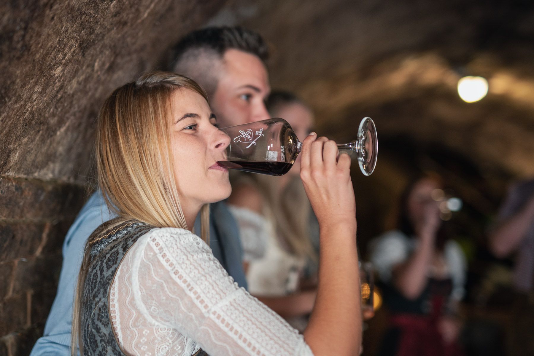 Žena pije víno ve vinném sklepě.