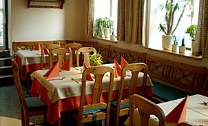 Útulná restaurace s prostřenými stoly a dřevěnými židlemi.