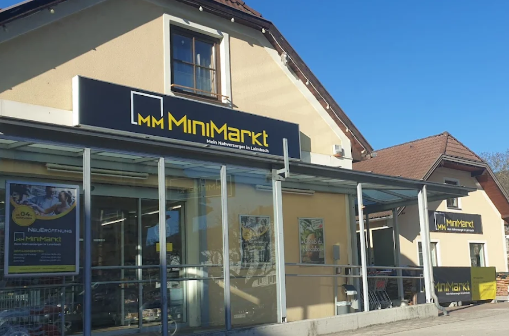 Vnější pohled na prodejnu MiniMarkt se skleněnou fasádou a reklamními plakáty.
