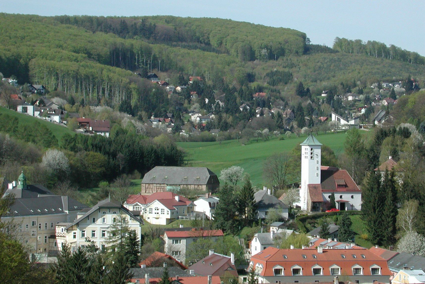Panorama Gablitzu s kostelem a okolními domy před zalesněnými kopci.