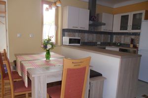 Moderní kuchyň a jídelní kout se stolem, židlemi a kuchyňským náčiním.