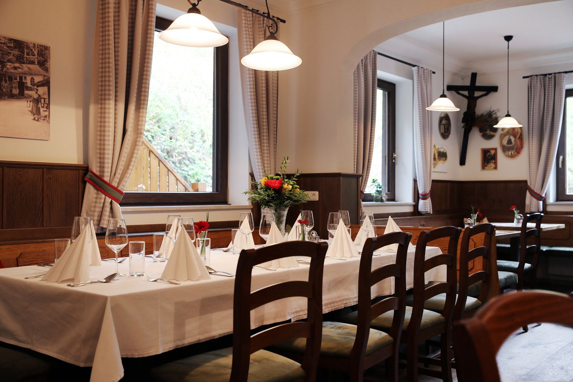 Interiér útulného hostince s prostřeným stolem, dřevěným nábytkem a dekoracemi na stěnách.