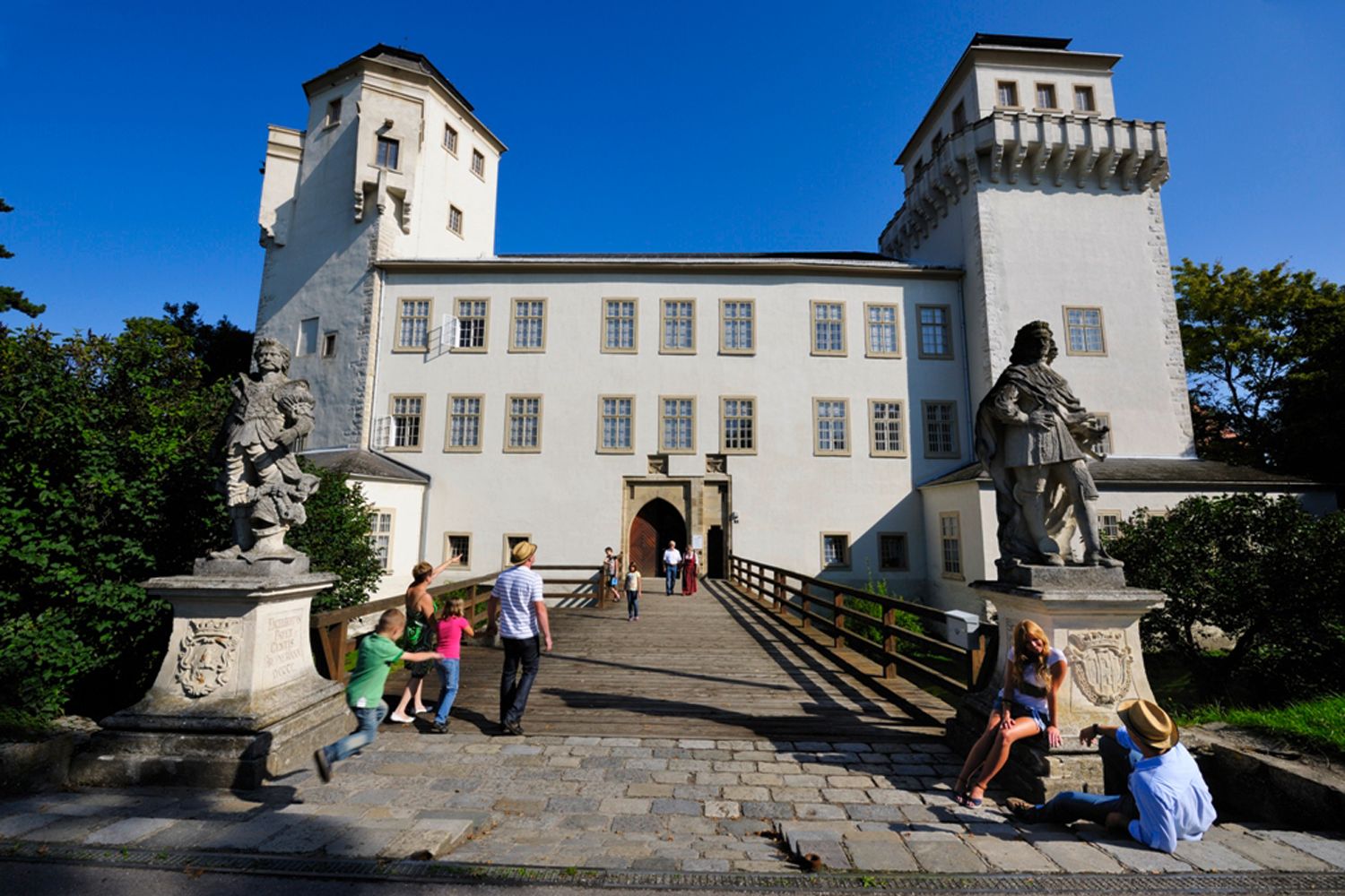 Hrad Asparn/Zaya s návštěvníky a sochami v popředí.