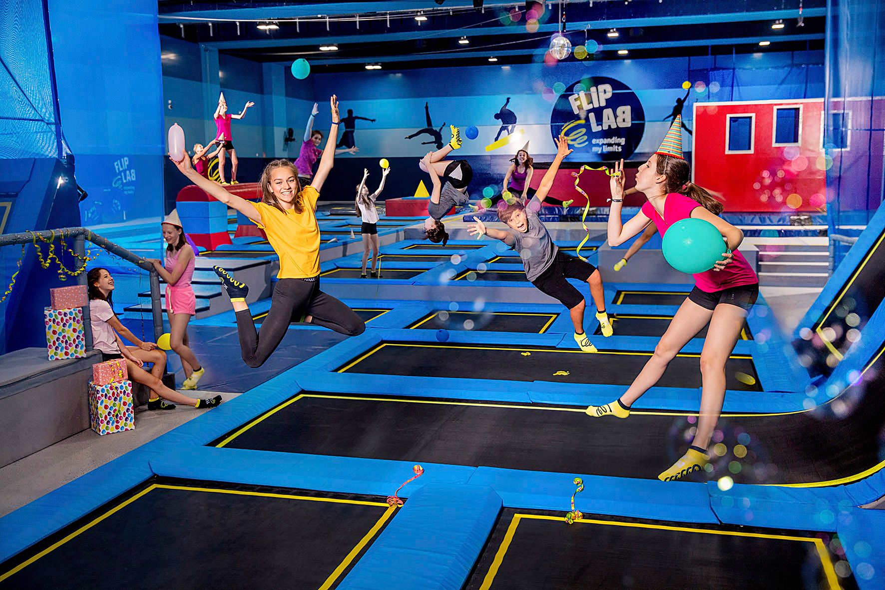 Lidé skáčou na trampolínách v hale s logem "Flip Lab".