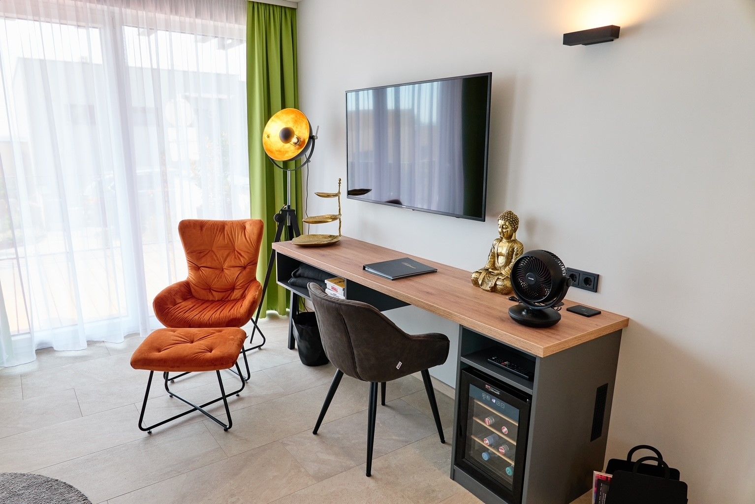 Obývací pokoj s křeslem, psacím stolem, sochou Buddhy a televizí.