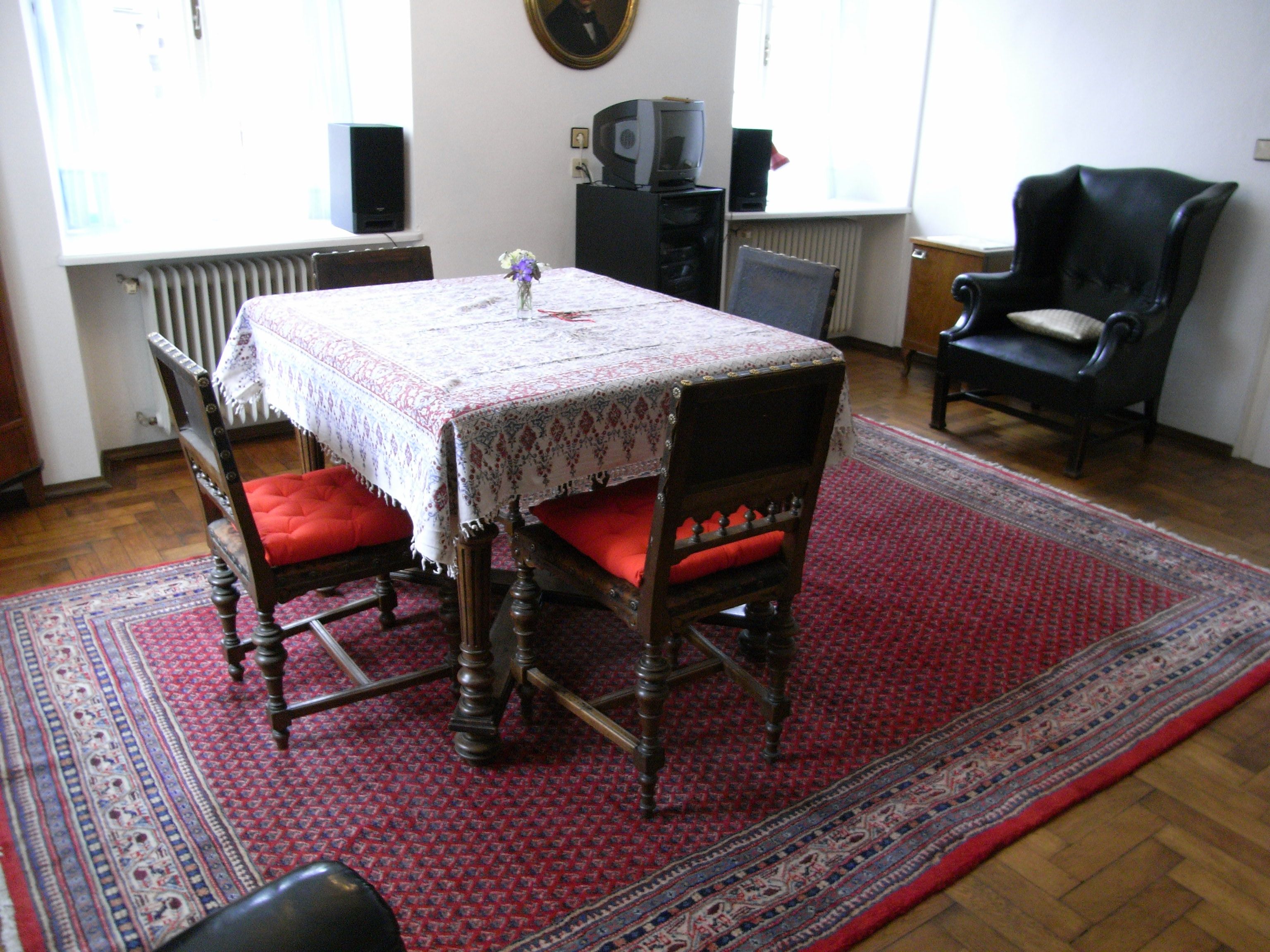 Obývací pokoj se stolem, židlemi a kobercem.