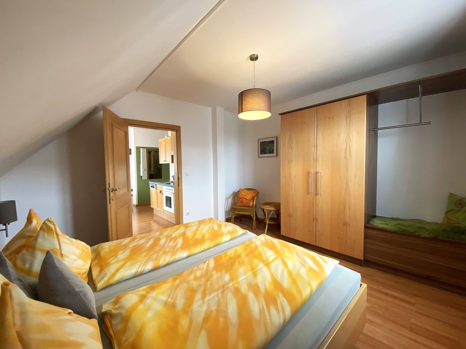 Ložnice s manželskou postelí, šatní skříní a výhledem do kuchyně.