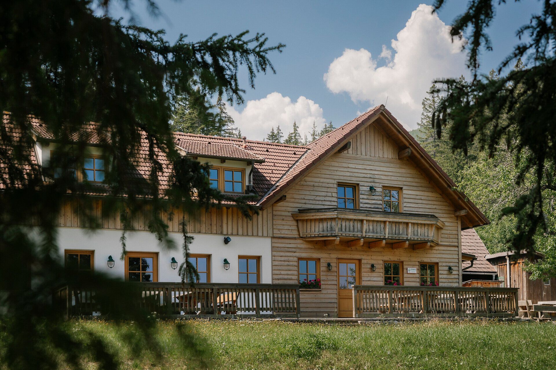 Vnější pohled na chatu Hengsthütte na Schneebergu s dřevěným balkonem a terasou