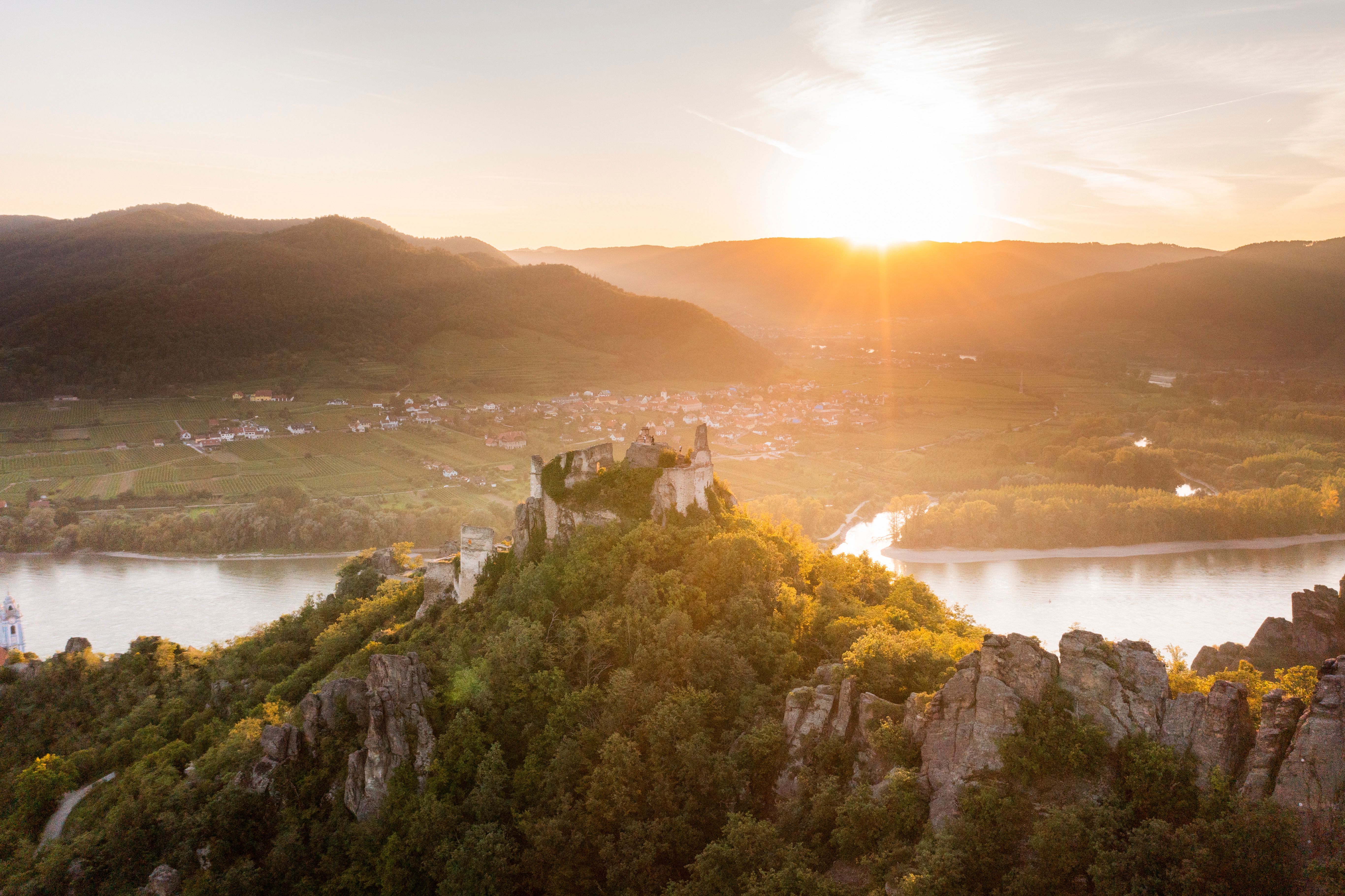 Die sanften Hügel und das glitzernde Wasser der Donau umrahmen die majestätische Ruine, die stolz über die Landschaft wacht. Bei Sonnenuntergang taucht das Licht die Umgebung in ein warmes Gold, während die bunten Blätter des Herbstes die Szenerie verzaubern. Ein perfekter Ort für Wanderer, die die Schönheit der Natur und die Geschichte der Region erleben möchten.