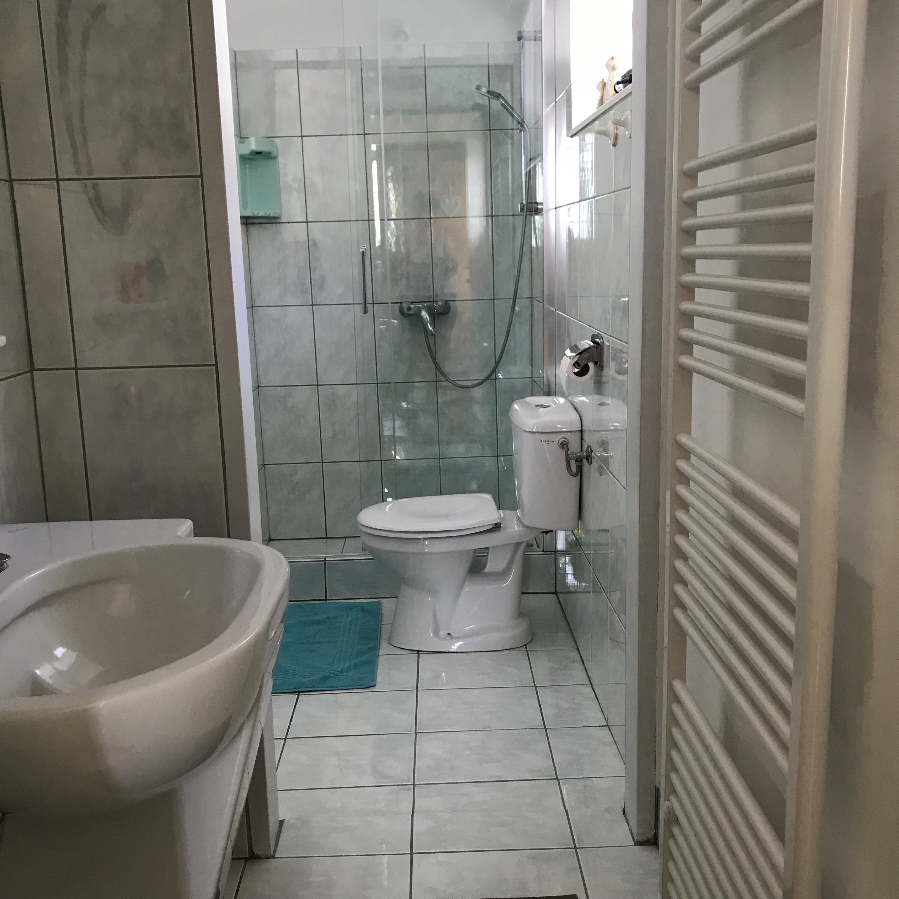 Moderní koupelna se sprchovým koutem, toaletou a umyvadlem.