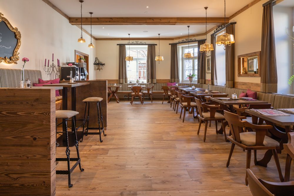 Útulný snídaňový kout s dřevěným nábytkem a velkými okny.