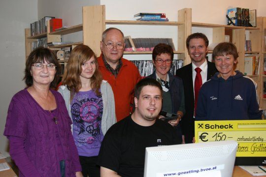 Skupina lidí v knihovně s šekem na 150 eur.