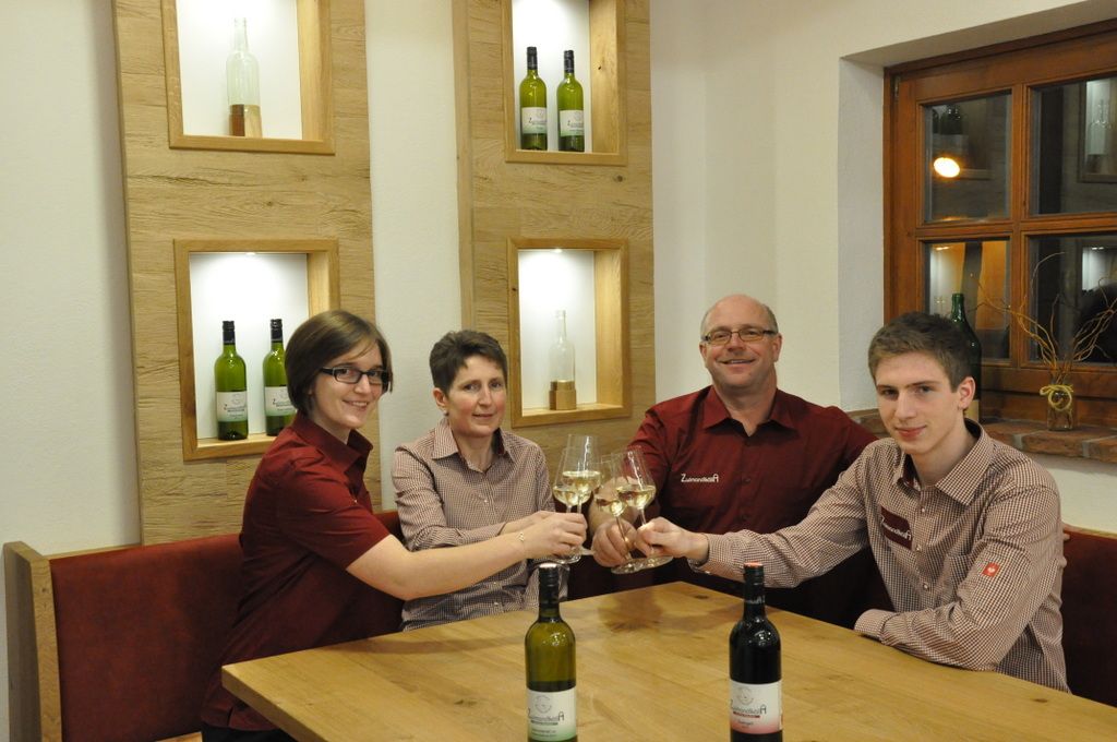 Čtyři lidé si u stolu cinknou skleničkami vína.