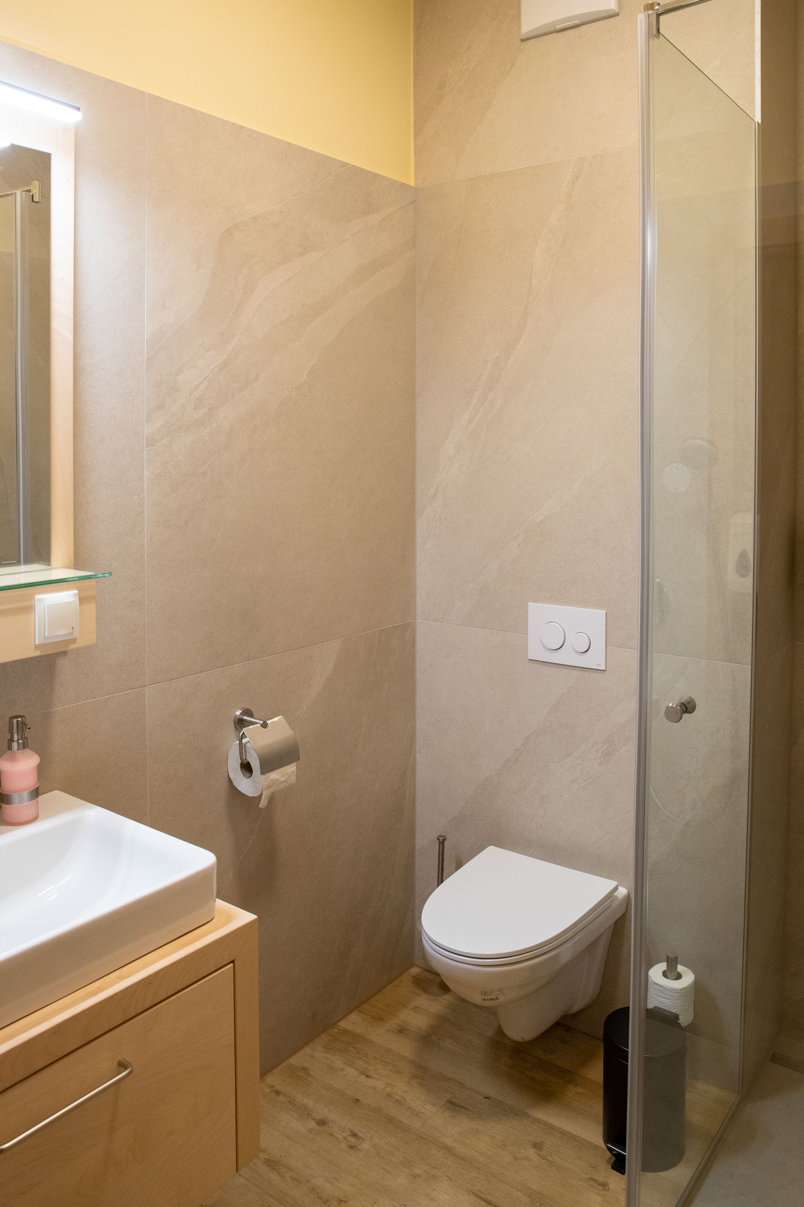 Moderní koupelna s umyvadlem, toaletou a sprchovým koutem.