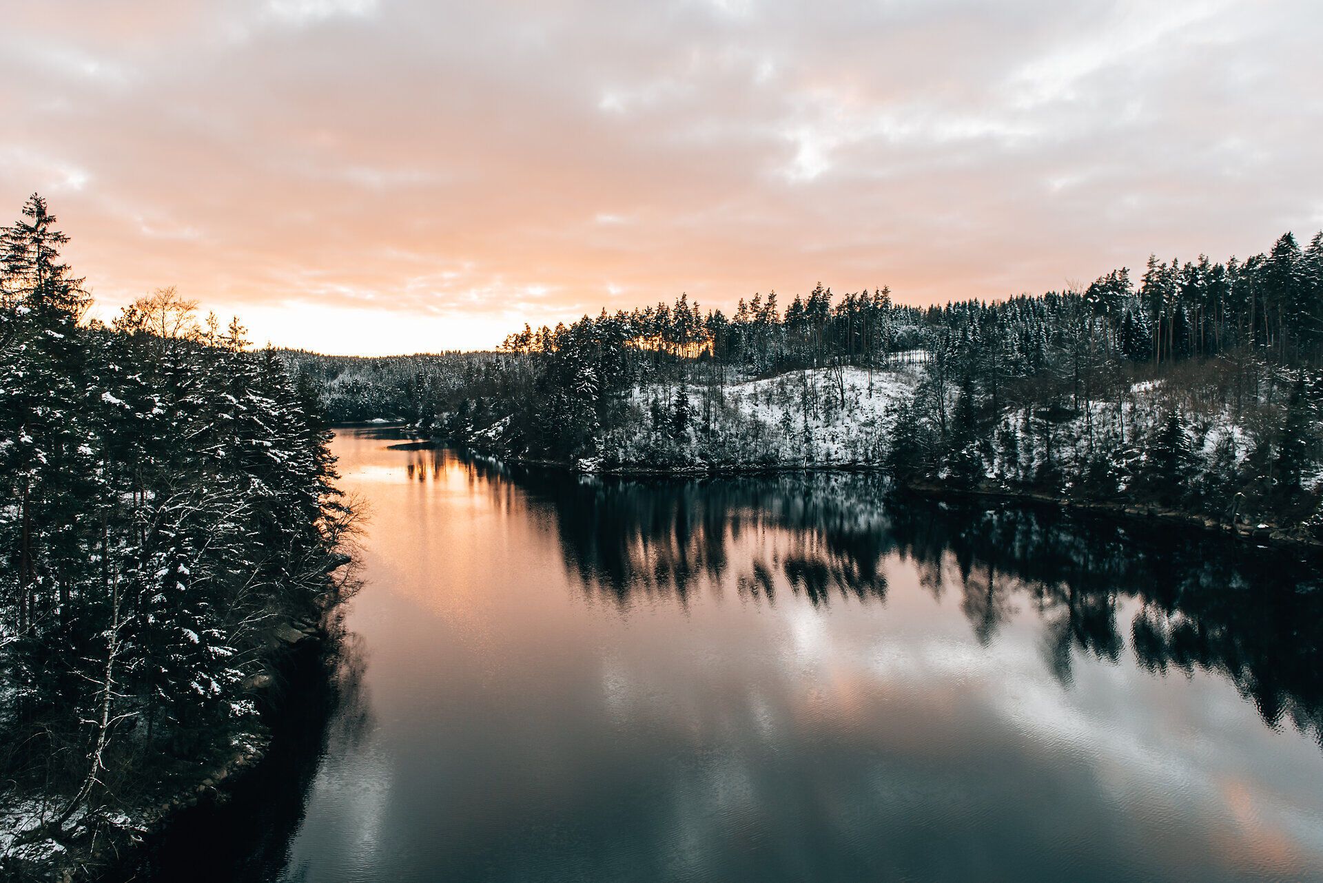 V mírných vlnách přehrady se odráží zasněžené břehy a zapadající slunce ozařuje oblohu teplými barvami. Krajinu obklopuje klidné ticho, které vybízí k setrvání a odpočinku.