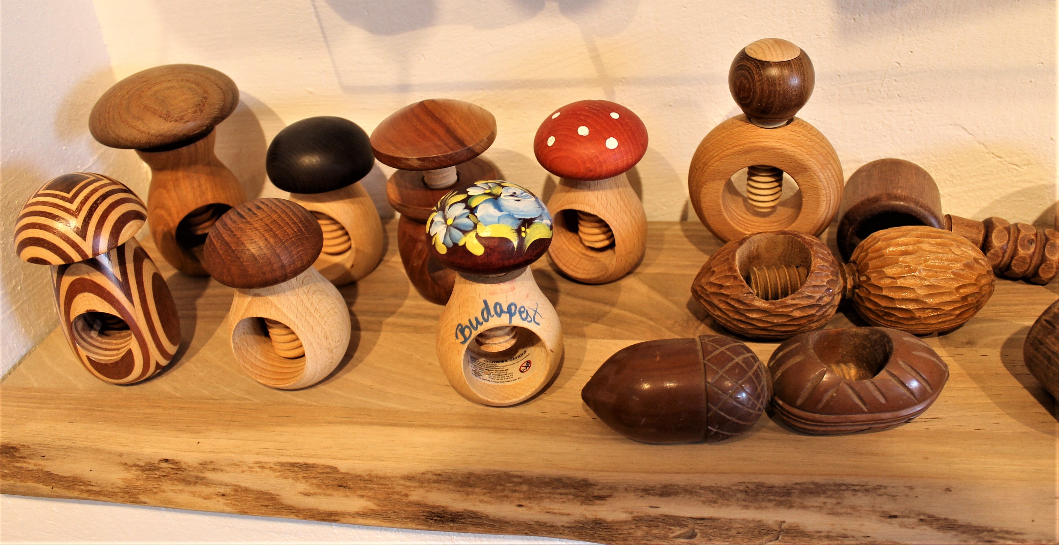 Různé dřevěné louskáčky ve tvaru hub na polici v Nusseum Krummnußbaum.
