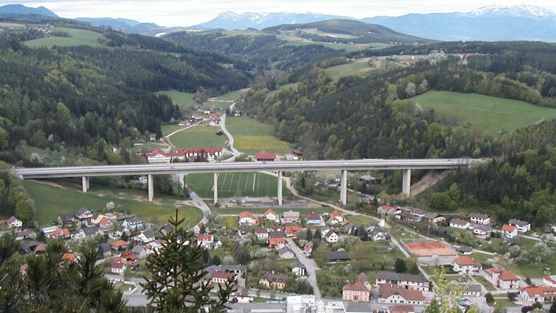Panoramatický výhled na obec Warth s mostem a okolními kopci.