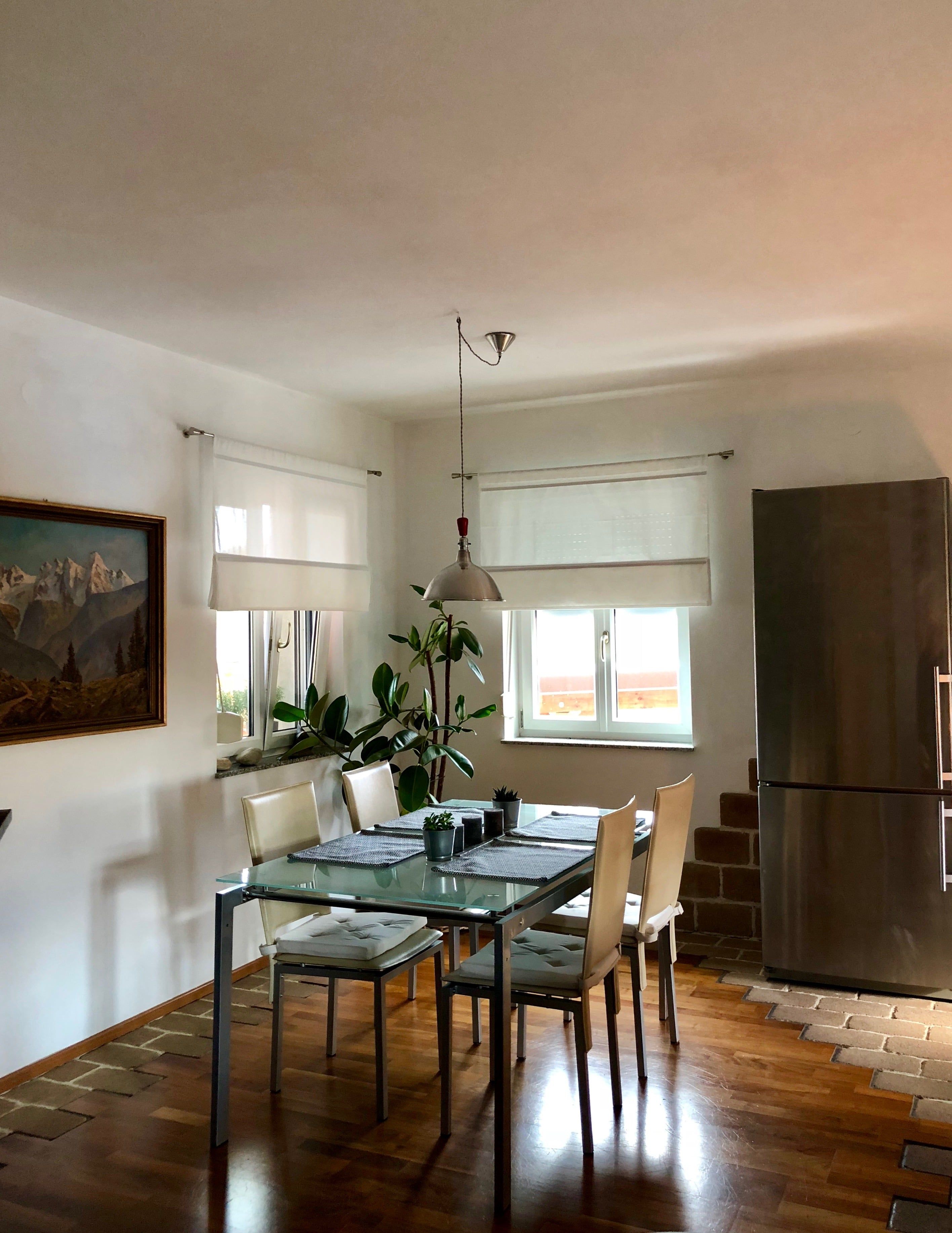 Otevřený obývací a jídelní prostor se stolem, židlemi a přirozeným světlem.