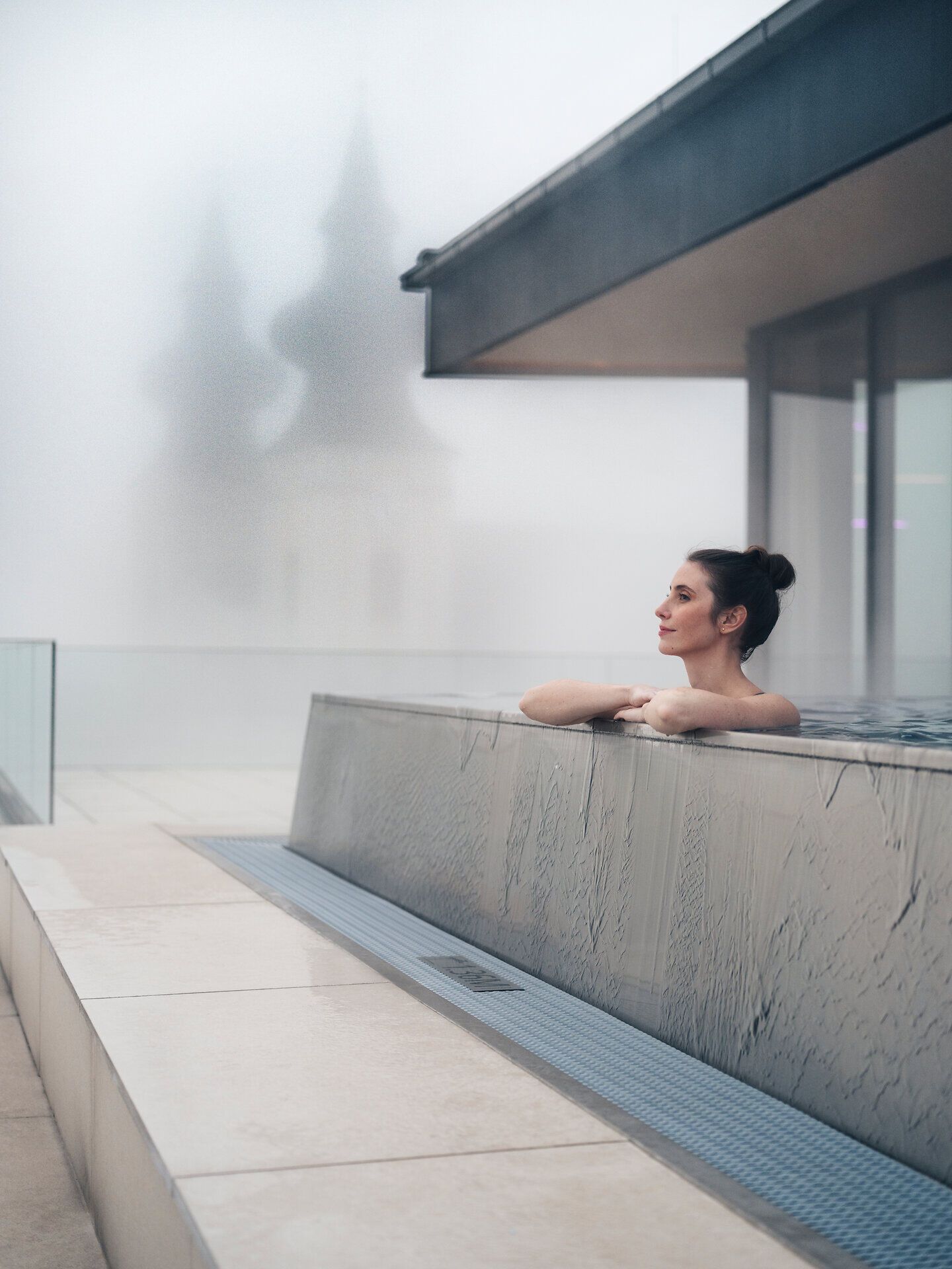 In einem stilvollen Infinity-Pool entspannen Sie und genießen den Blick auf die sanften Hügel, die in mystischen Nebel gehüllt sind. Die ruhige Atmosphäre lädt dazu ein, die Seele baumeln zu lassen und die Schönheit der Natur zu erleben.