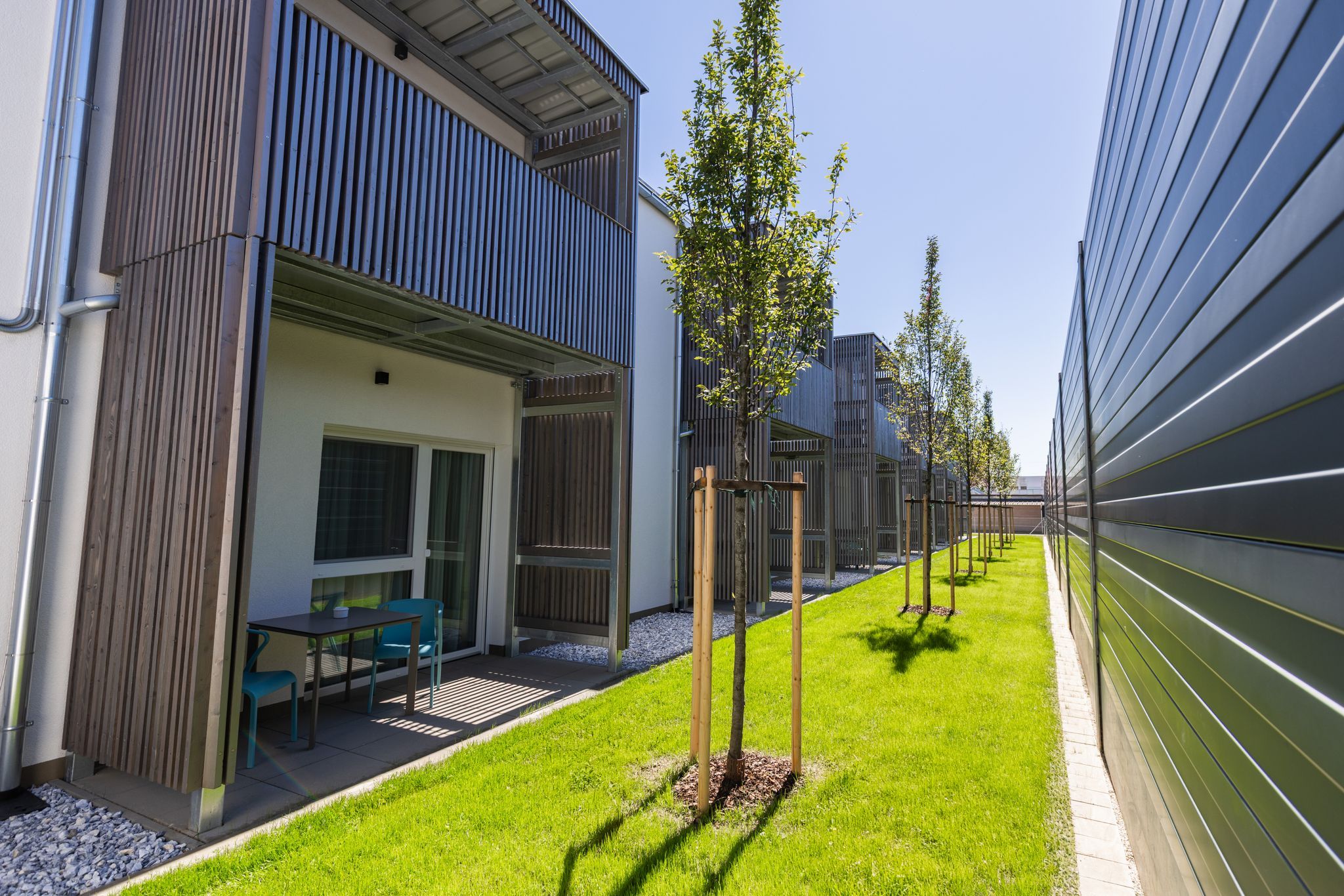 Moderní bytový komplex s balkony a upraveným trávníkem.