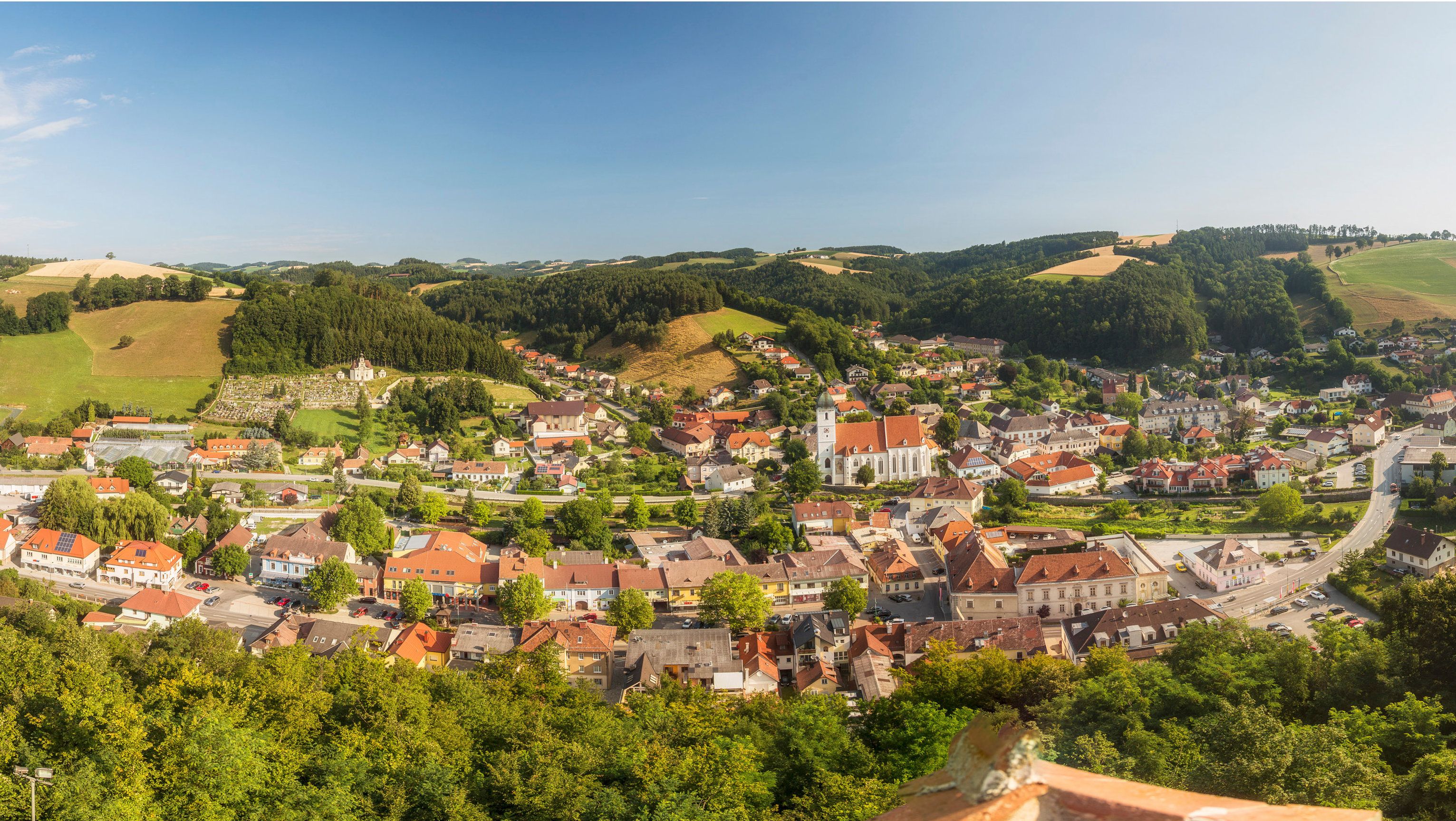 Panoramatický pohled na Kirchschlag in der Buckelige Welt s kostelem a okolními kopci.