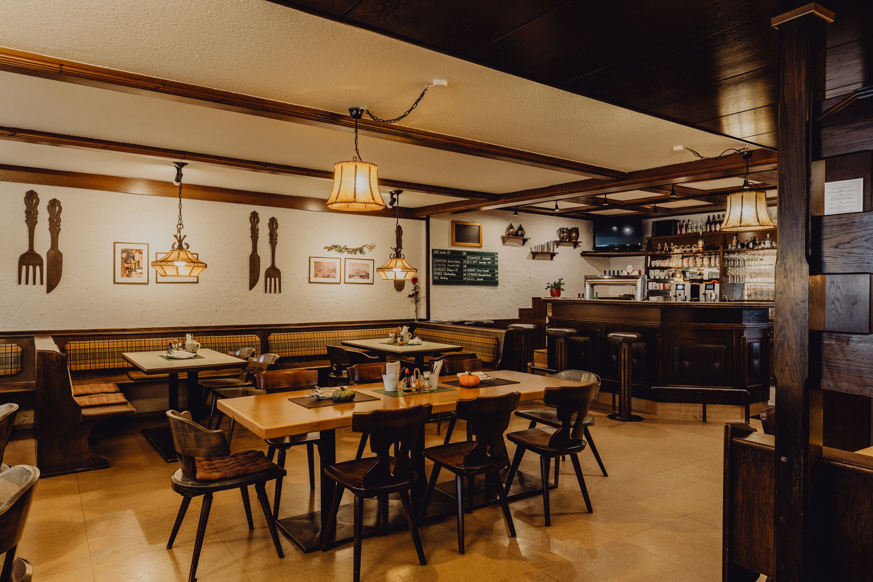 Útulná hospůdka s dřevěným nábytkem, barem a dekorativními lampami.