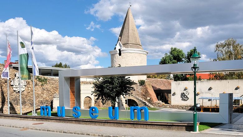 Vchod do Hornova muzea s moderním nápisem a historickou věží v pozadí.