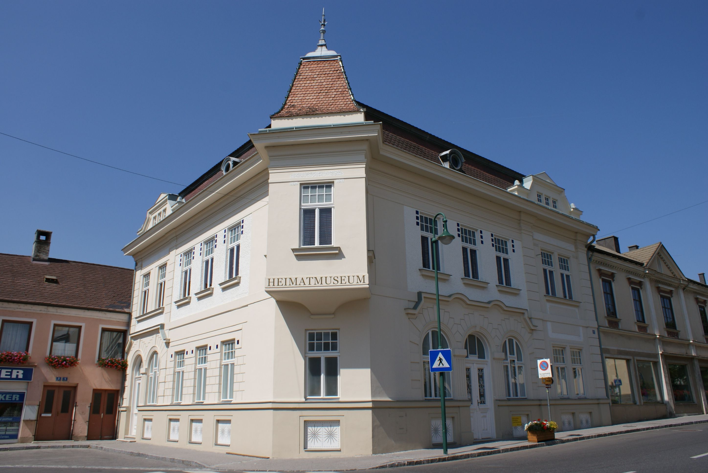 Historická budova s nápisem "Heimatmuseum" v rakouském Manku pod jasnou oblohou.