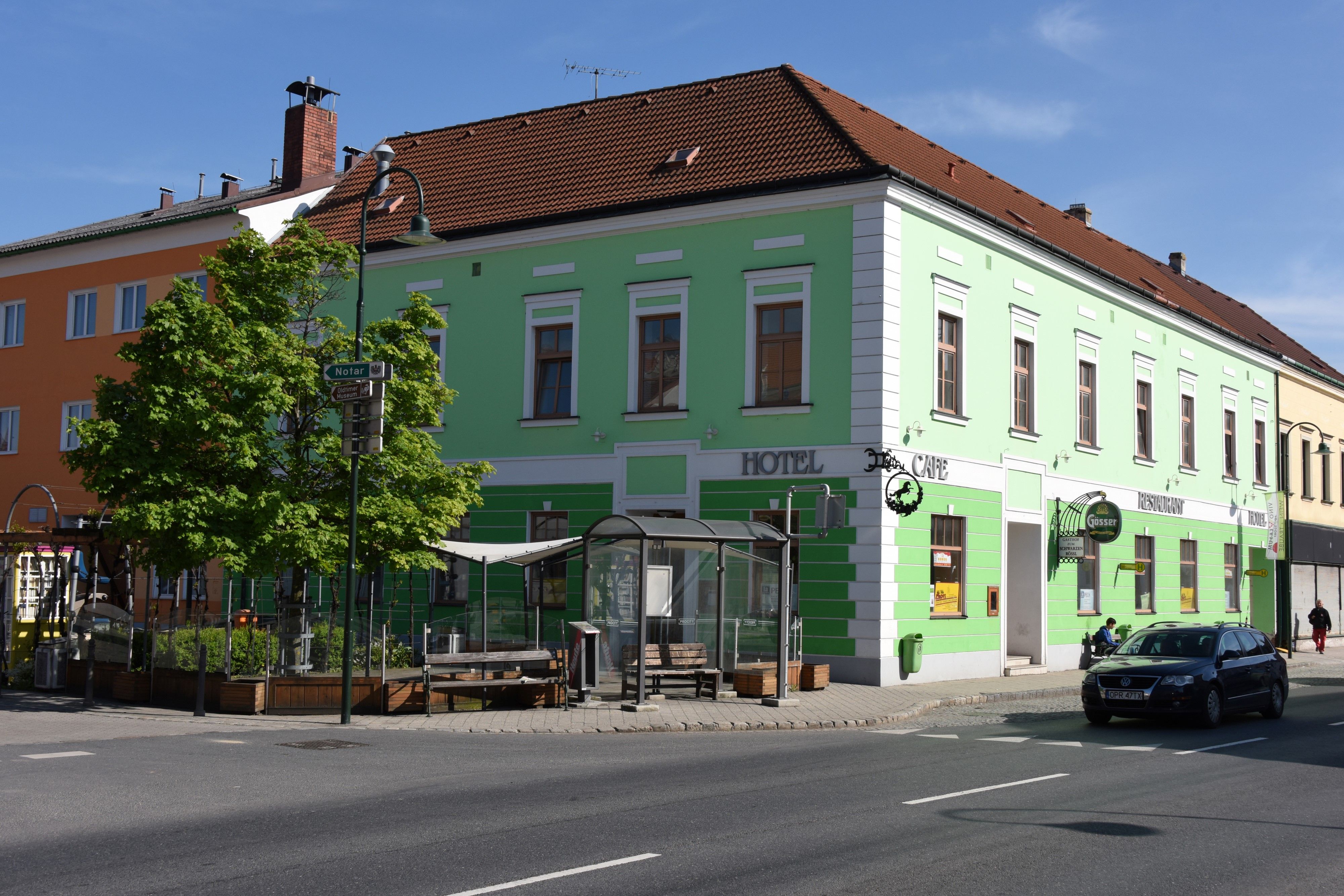 Zelená budova s nápisy hotel a kavárna na rohu ulice.